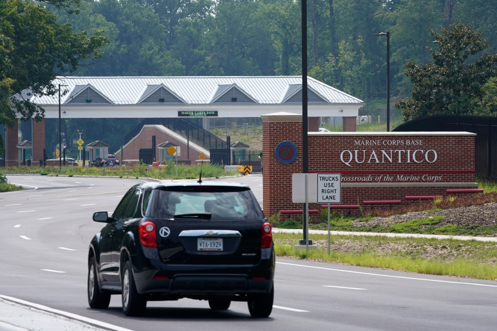 Traffic drives past an entrance sign of Marine Corps Base Quantico
