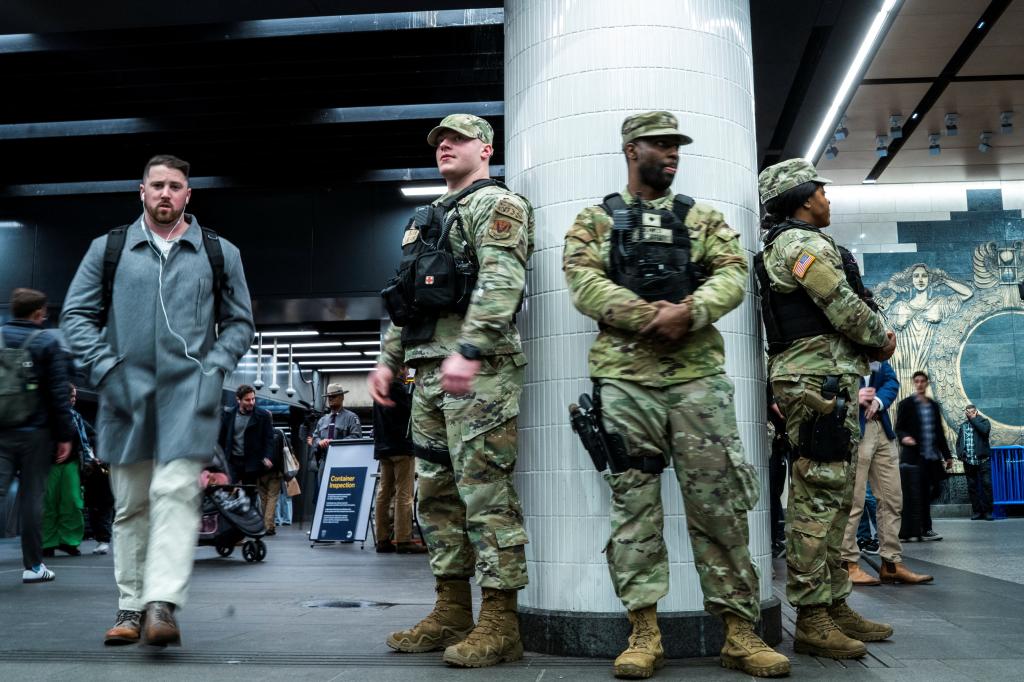 Members of the New York State National Guard keep an eye on commuters as they stand guard in a check point inside the entrance of subway station in New York City, U.S., March 7, 2024.