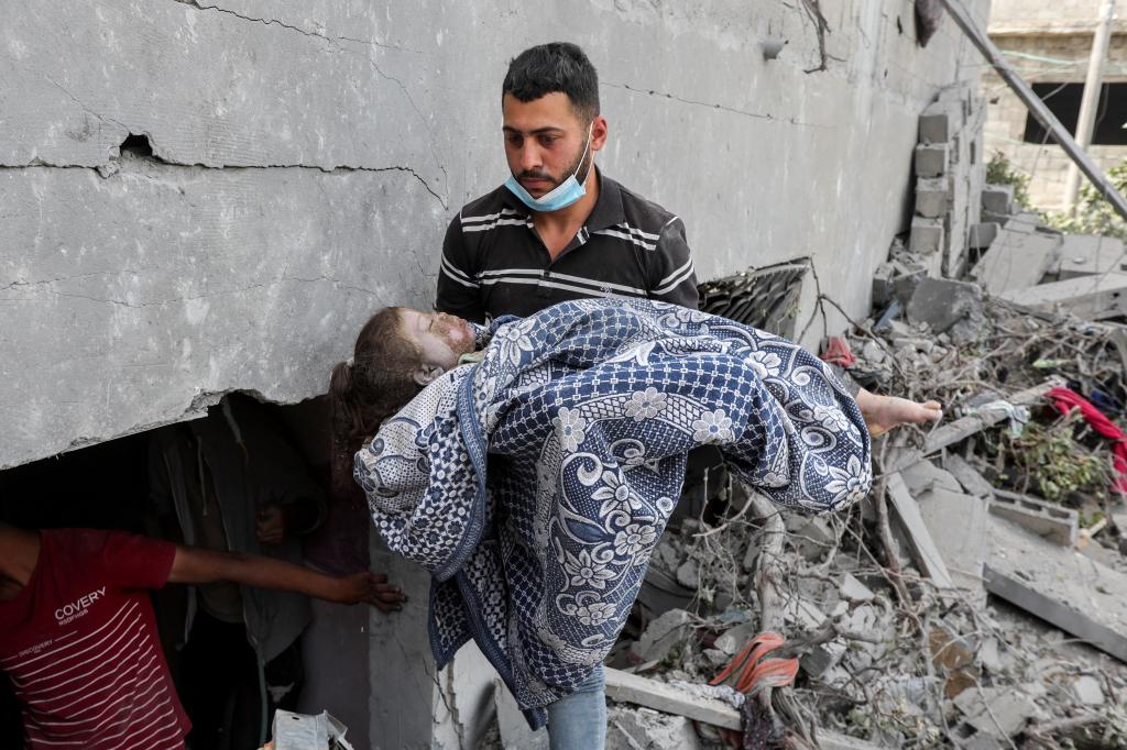 A man carries the dead body of a Palestinian child recovered from a house hit by an Israeli strike, in Nuseirat, in the central Gaza Strip, May 19, 2024. 