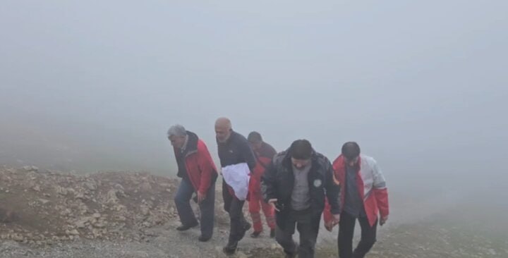 Men climbing a mountain in the fog