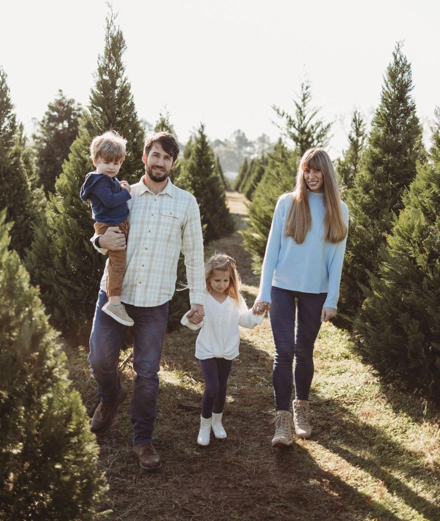 Lukenas, his wife and two young kids walking through trees.