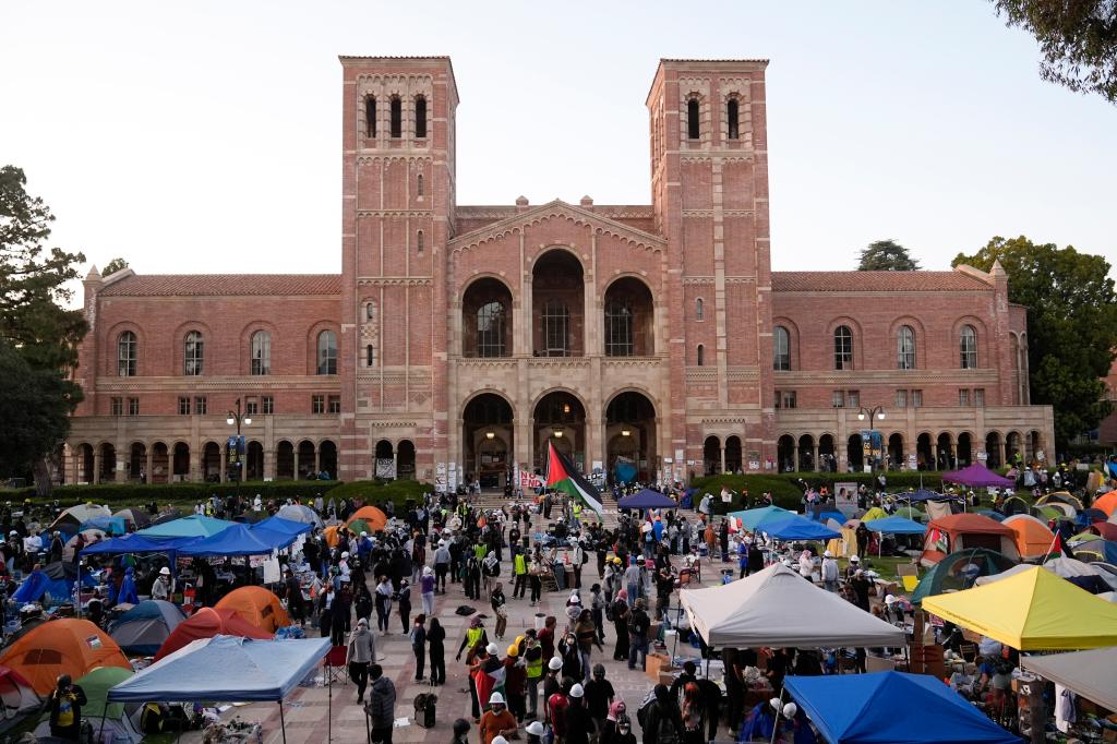 Demonstrators walk in an encampment on the UCLA campus after clashes between pro-Israel and pro-Palestinian groups, Wednesday, May 1, 2024, in Los Angeles.