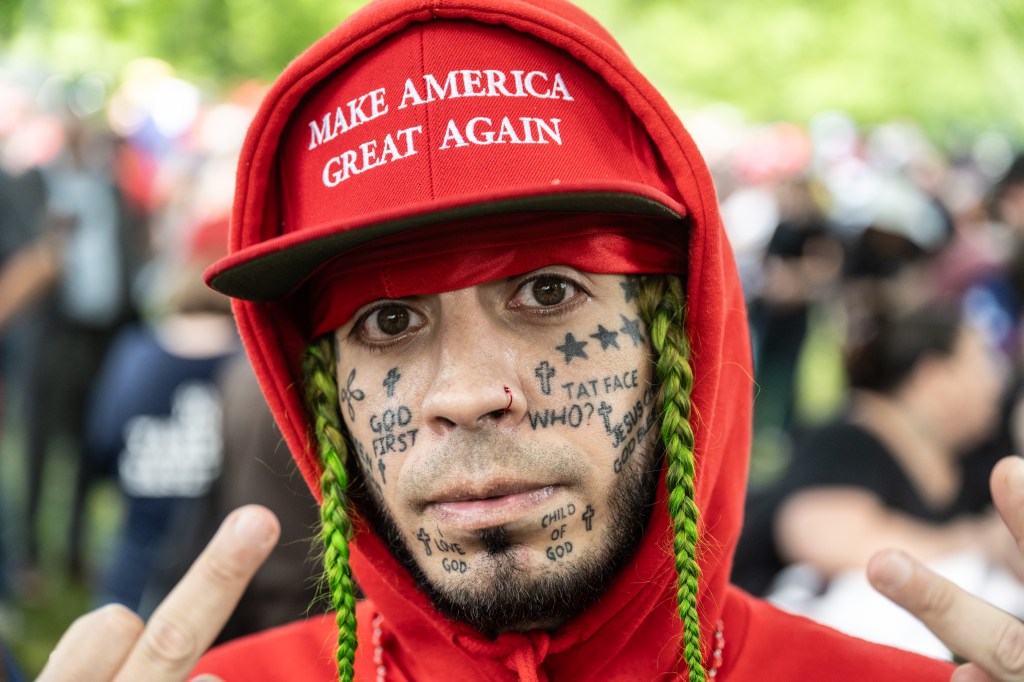 A supporter of former U.S. President Donald Trump poses for a photo as people gather outside of the Crotona Park rally venue.