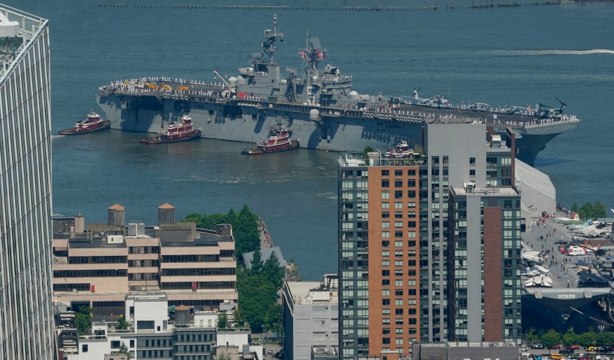 Tugboats maneuver the USS Bataan.