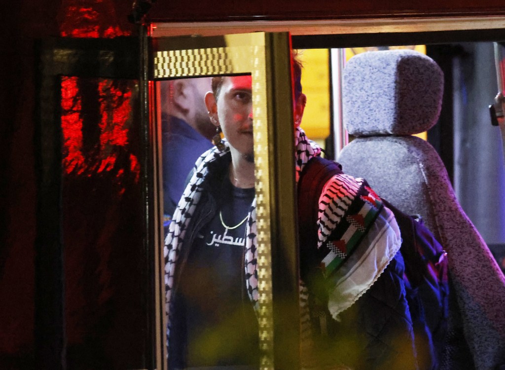 A man in a keffiyeh stares out a bus window