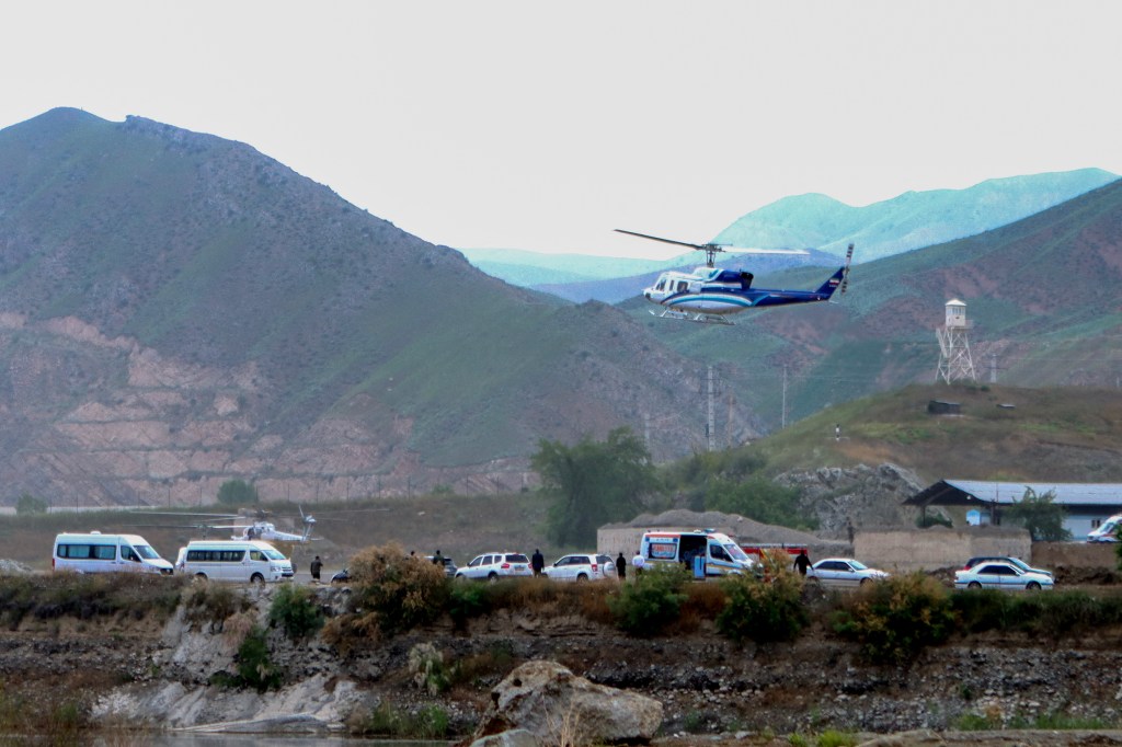 A blue and white helicopter taking off in a mountainous region