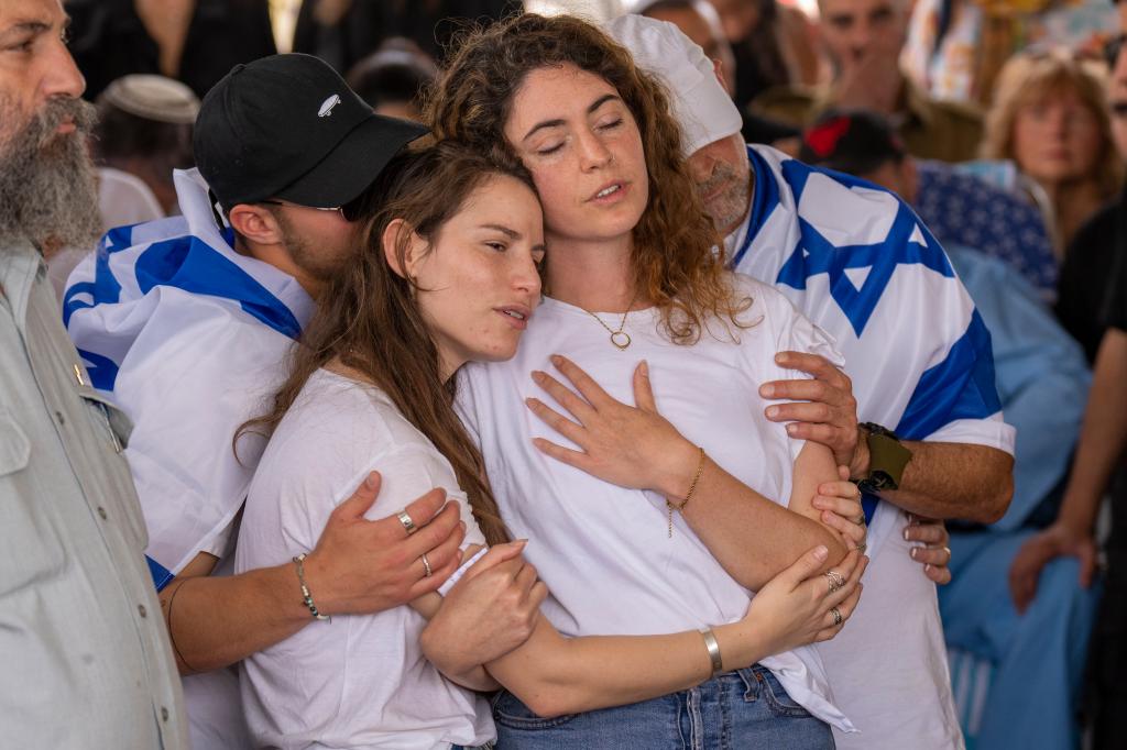 Shir Sage, enter, fiancee of Israeli reserve soldier Major Dor Zimel, holds her heart in grief during his funeral in Even Yehuda, Israel, Monday, April 22, 2024.