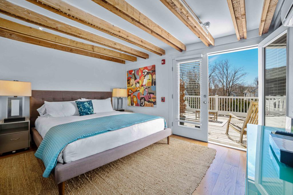 A bedroom in The Zey Hotel of Hampton Hotels, featuring a bed and a door leading to a deck.