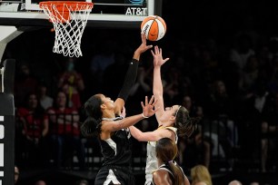 Aces center A'ja Wilson (left) blocks a shot by Fever guard Caitlin Clark during the first half Saturday in Las Vegas.