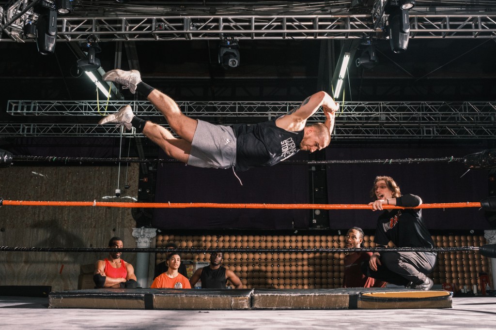 Charles Mason soars through the air in a wrestling at the House of Glory wrestling school, as a few men watch in amazement. 