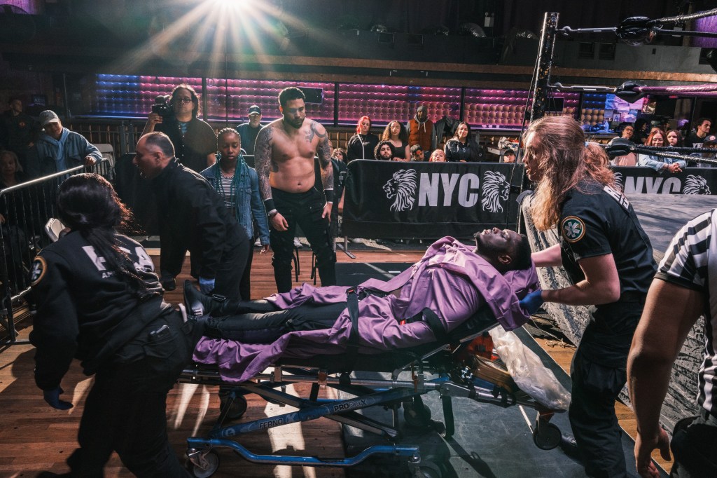Paramedics take away a man on a stretcher, covered in a purple blanket, at the House of Glory wrestling school.