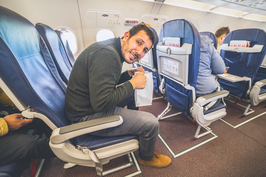 Man sitting in an airplane looking scared and unwell due to air sickness