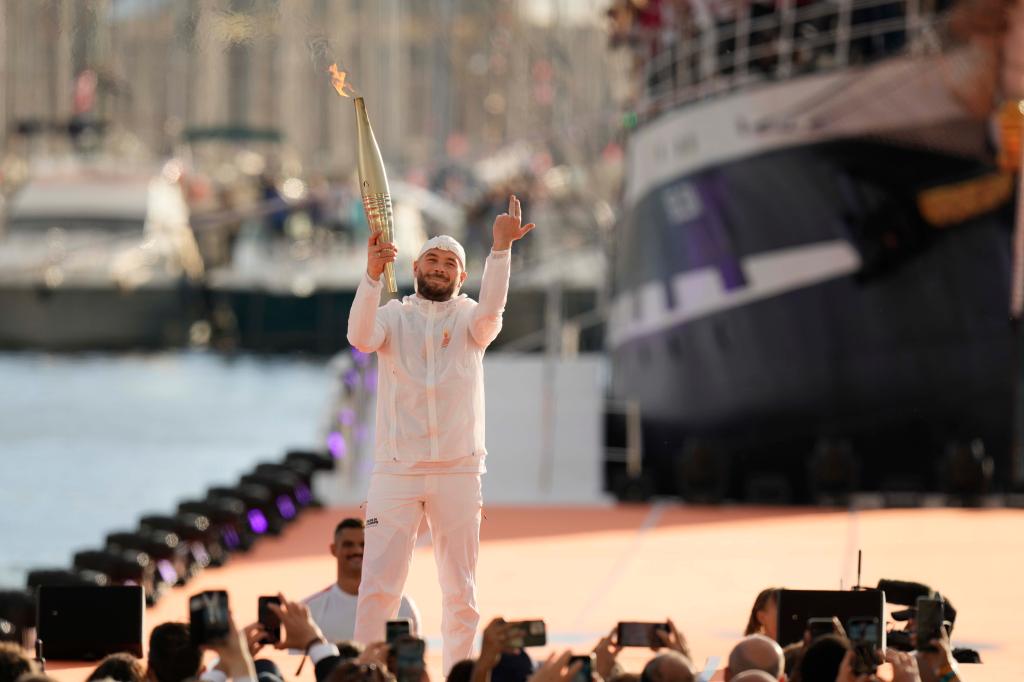 French rap artist Jul holds the Olympic torch during the torch arrival ceremony in Marseille, southern France, Wednesday May 8, 2024.