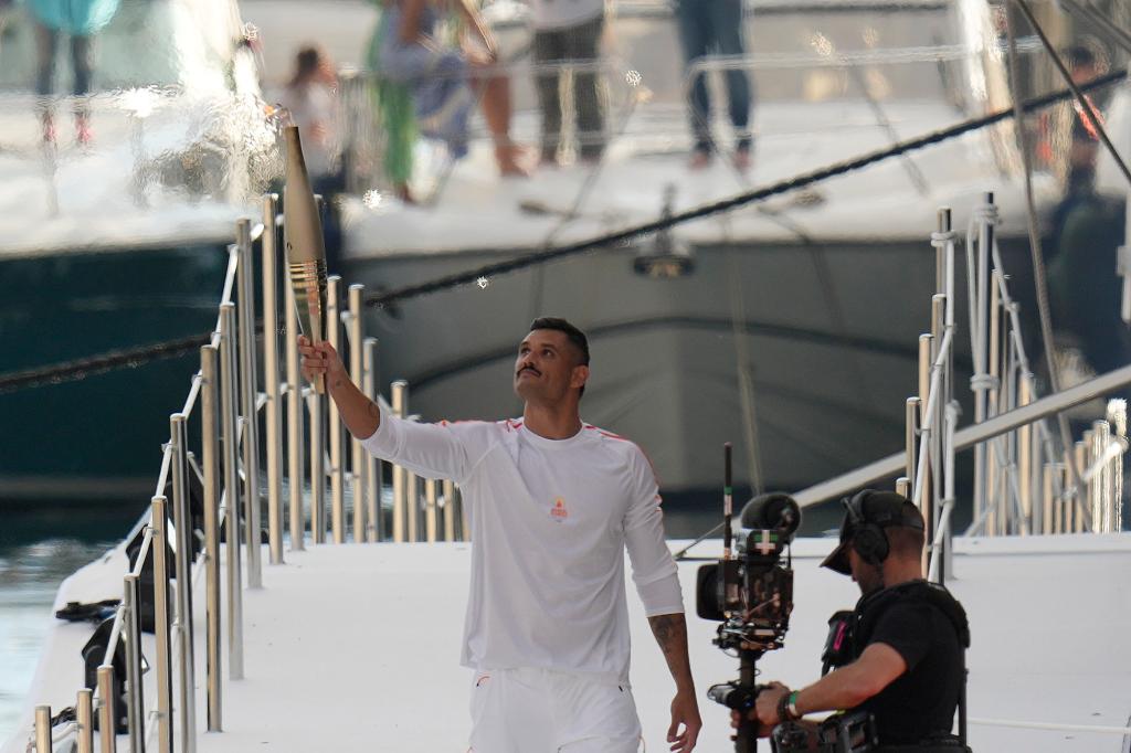 First torch carrier in France French Olympic swimmer Florent Manaudou holds the Olympic torch after leaving The Belem, the three-masted sailing ship in the Old port of Marseille, southern France, Wednesday, May 8, 2024. 