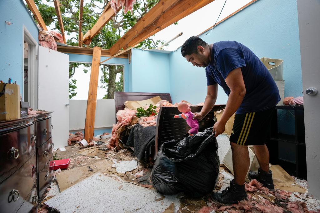 A man cleaning out a bedroom after the storm blew away his home's roof on May 17, 2024.