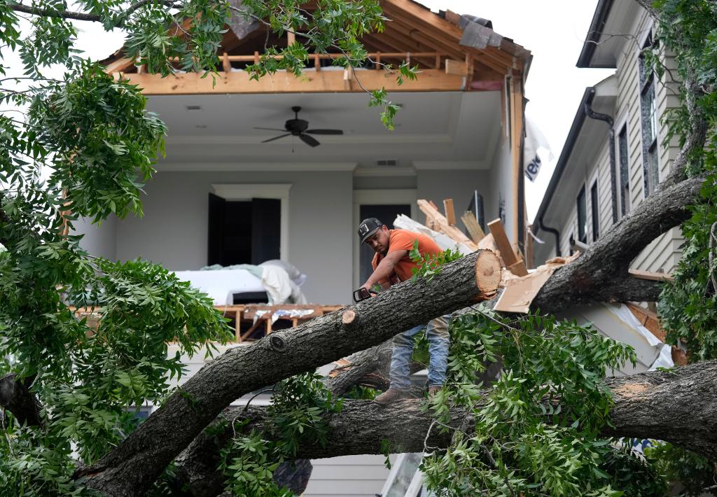 A man cutting a tree that fell on a house in Houston.