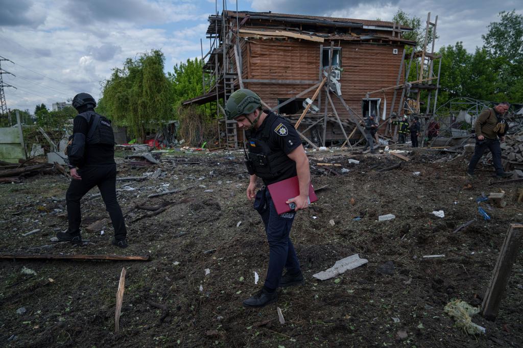 Ukrainian police officers look for fragments of a glide bomb in front of damaged house after a Russian airstrike on a residential neighborhood in Kharkiv, Ukraine, Saturday, May 18, 2024.