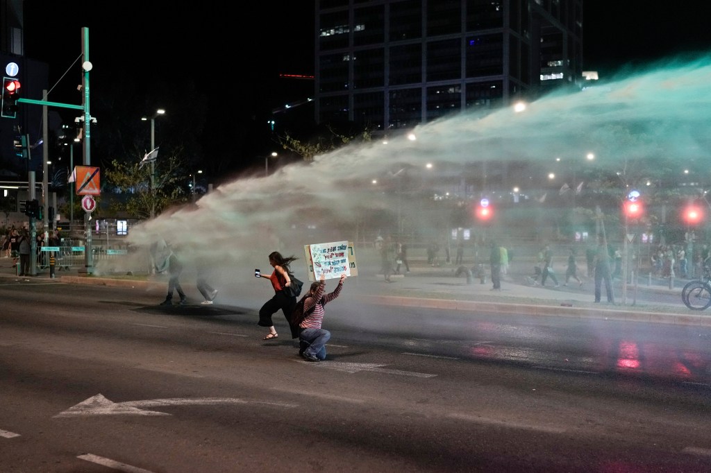 Police use water cannon to disperse demonstrators blocking a road during a protest 