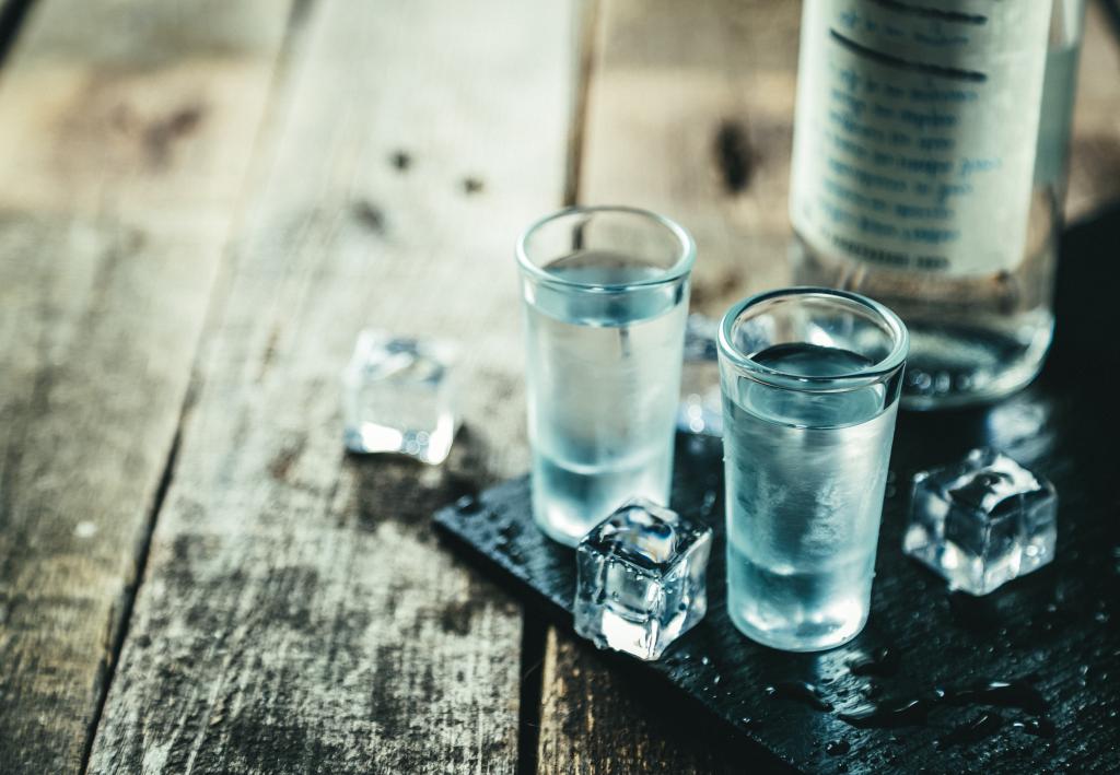 Traditional greek vodka - ouzo in shot glasses on rustic wood background