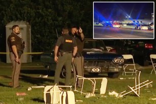 Police officer standing next to a car at the scene of a shooting in Alabama