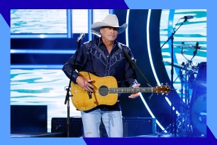 Alan Jackson plays guitar onstage.