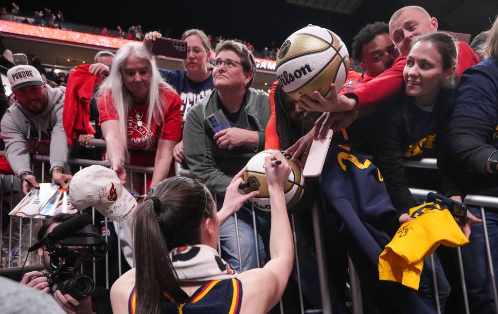 Caitlin Clark signs autographs for fans after the Fever's preseason win over the Dream.