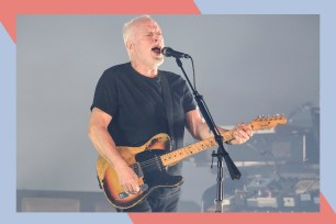 David Gilmour sings while playing guitar in concert.