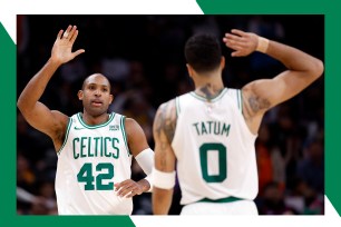 Celtics star Al Horford (L) jogs toward teammate Jayson Tatum to high five him.