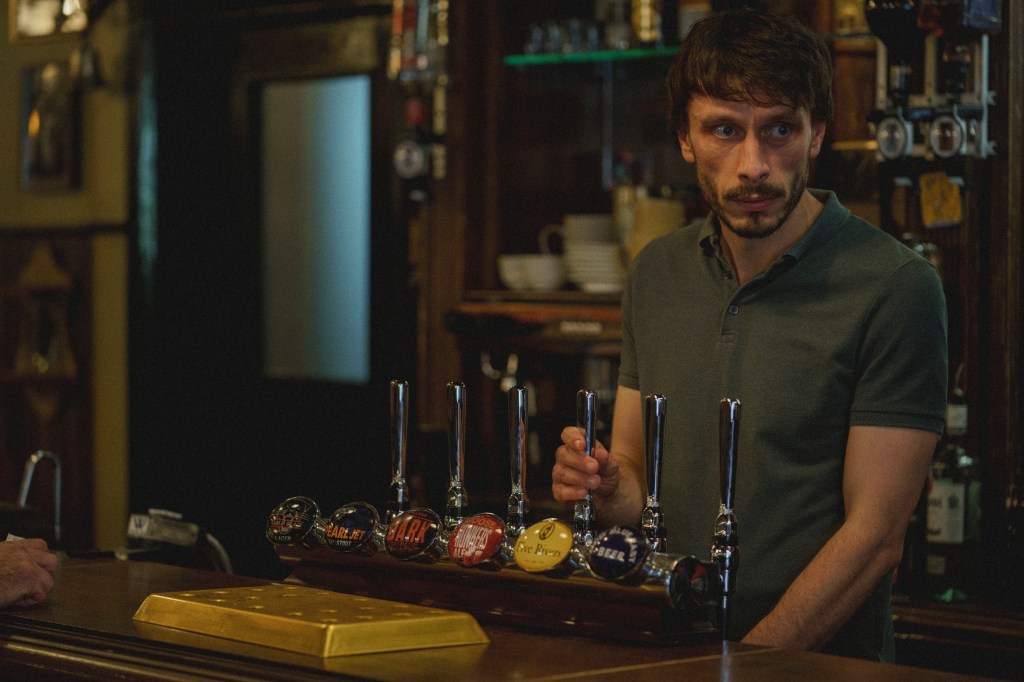 Richard Gadd standing behind a bar. 