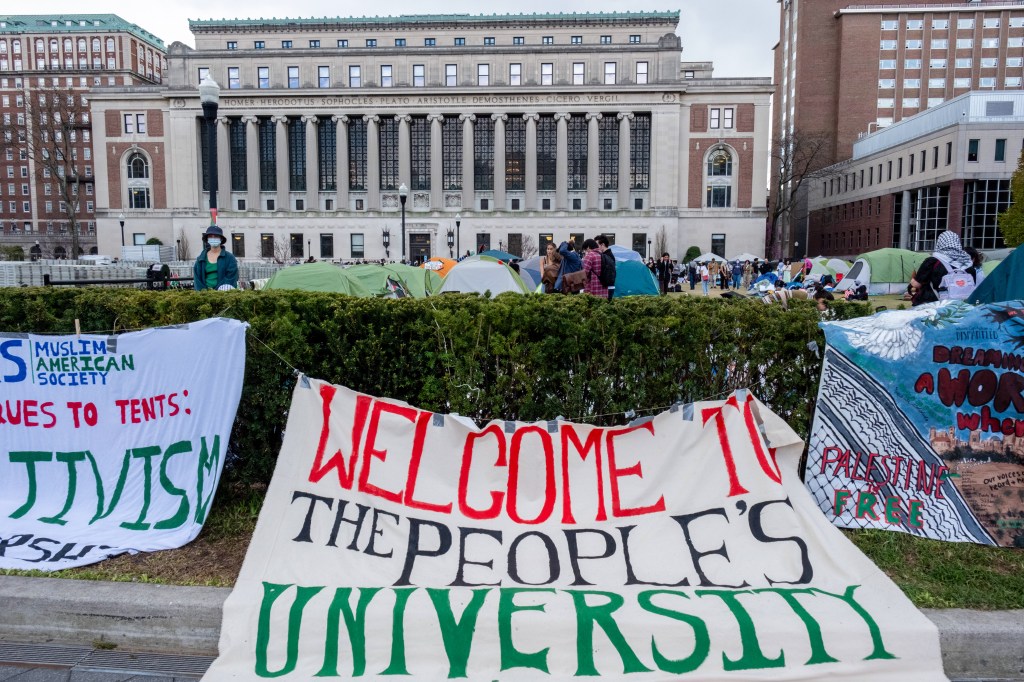 Banners hang on the hedge in front of the encampment in front of Butler Library at Columbia University.