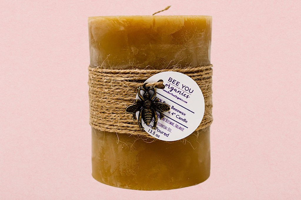 A candle wrapped in twine with a bee on it against a fresh green paper texture background