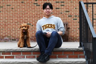 Student Brian Chan sitting on a step with Tigger, the schools therapy dog, at Staten Island Academy