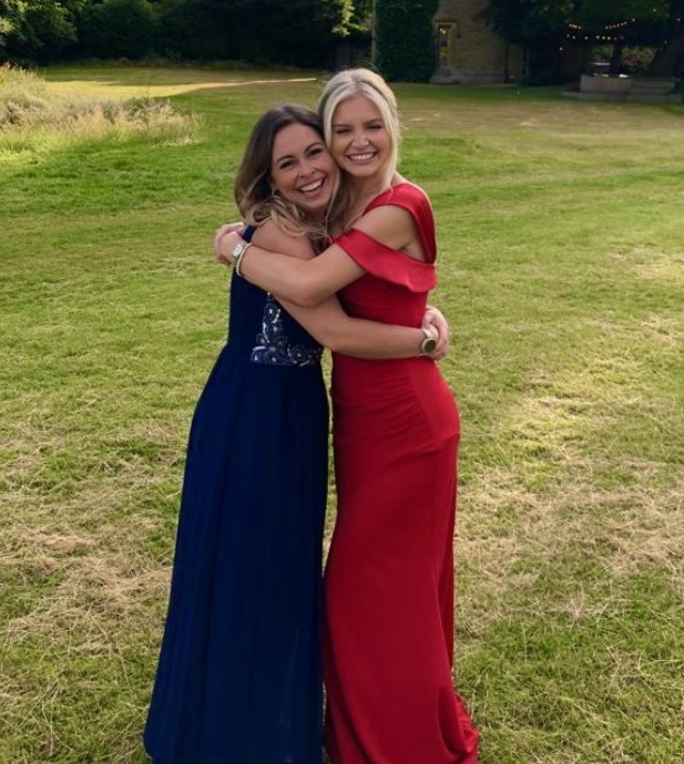 Sophie Hare and Rachel Fletcher, standing in a grassy field and hugging each other