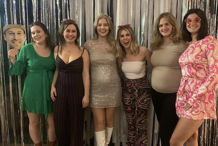 Six women standing together, five of whom are pregnant, including the bride and her four bridesmaids.