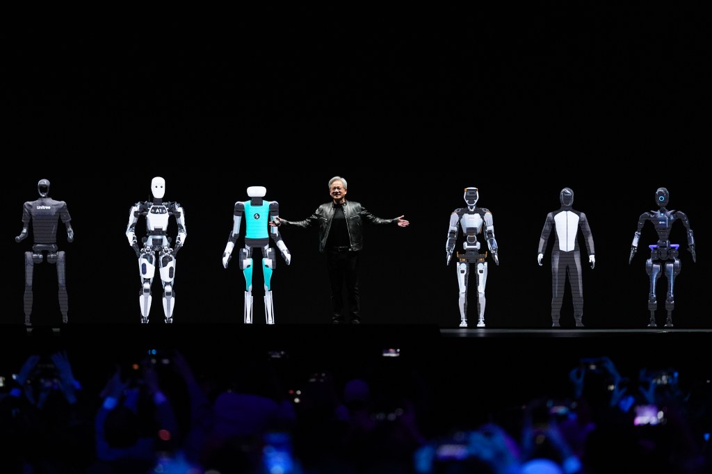 Huang gestures while standing amidst images of robots last month.