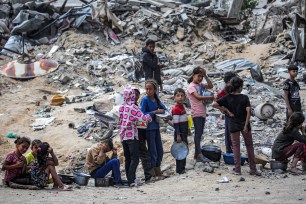 Children wait with pots to receive food rations from an outdoor kitchen in Khan Yunis in the southern Gaza Strip