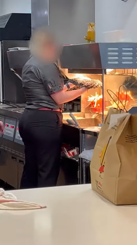 McDonald's employee drying a mop under the heat lamp of the French fry station
