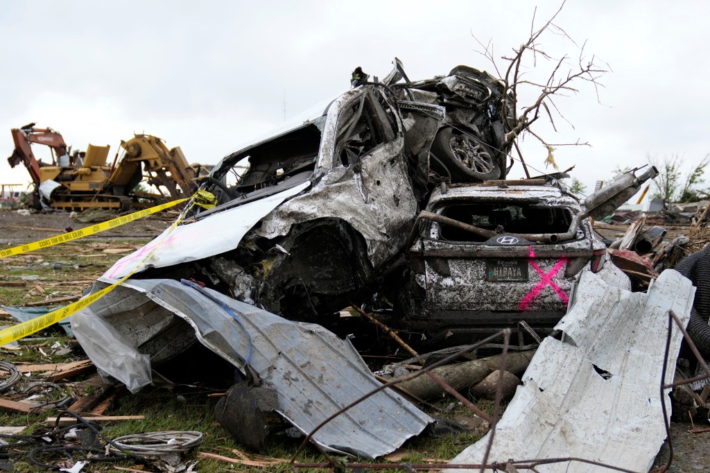 Cars lay busted and bent while damaged houses sat skewed against the gray and overcast sky. 