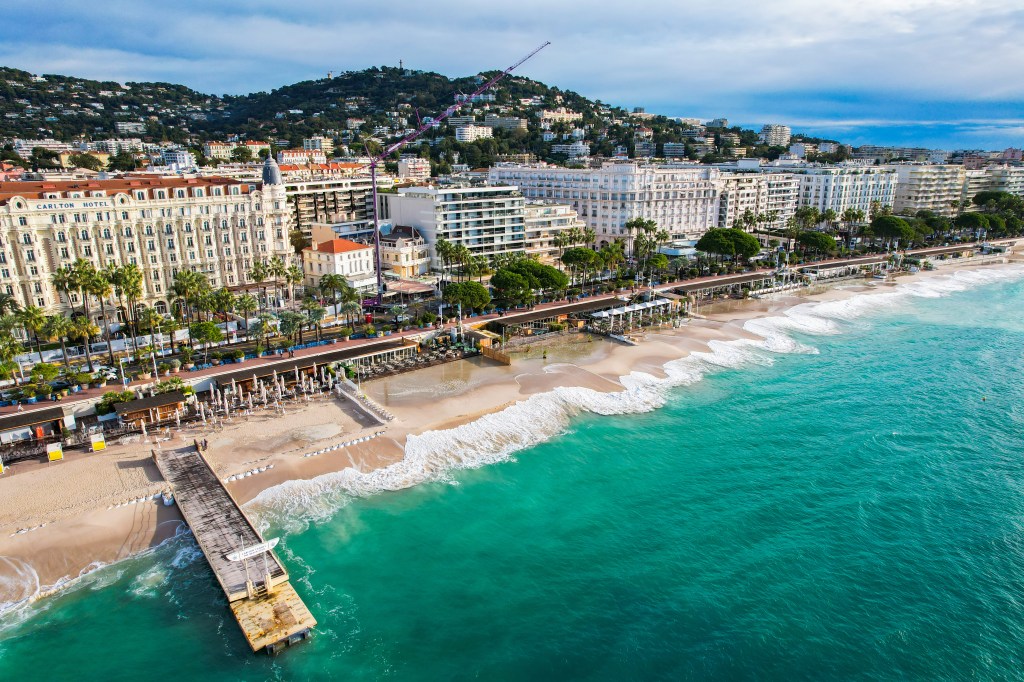 Aerial view of Cannes city with a focus on the Croisette waterfront and beach, known for the famous Cannes Film Festival