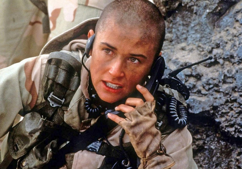 Demi Moore with a shaved head in military uniform talking on a phone for the film 'GI Jane', directed by Ridley Scott