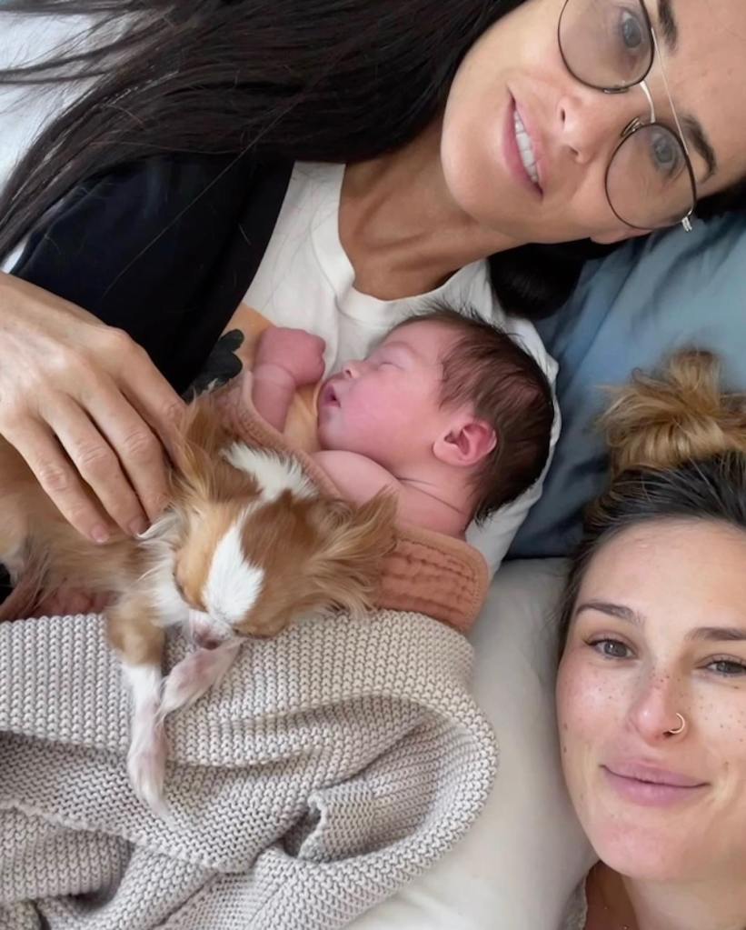 Demi Moore lovingly holding her first grandchild, Louetta, with daughter Rumer and a dog nearby