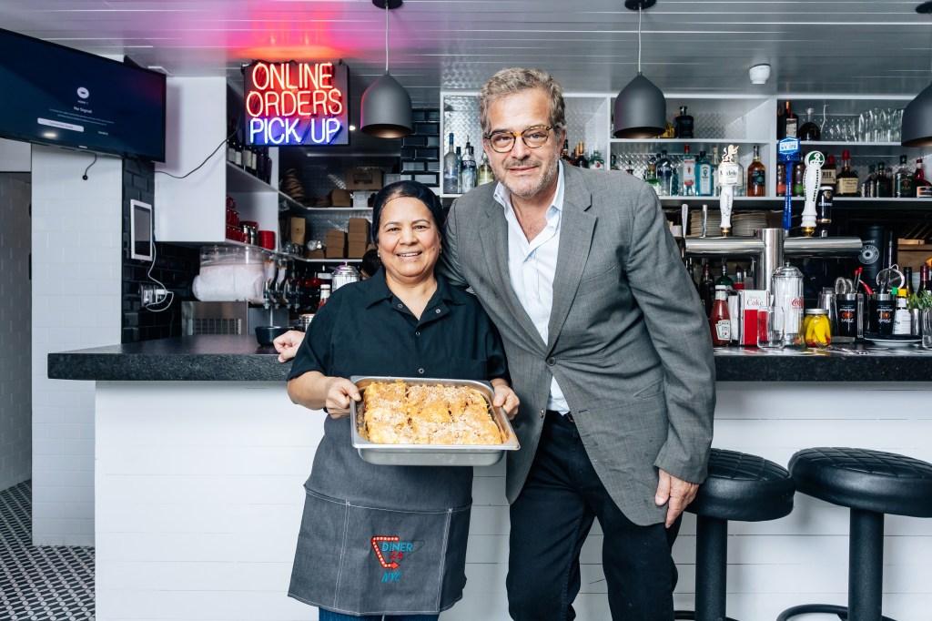A man and woman at Diner 24 in Manhattan, holding a tray of traditional Greek baked goods