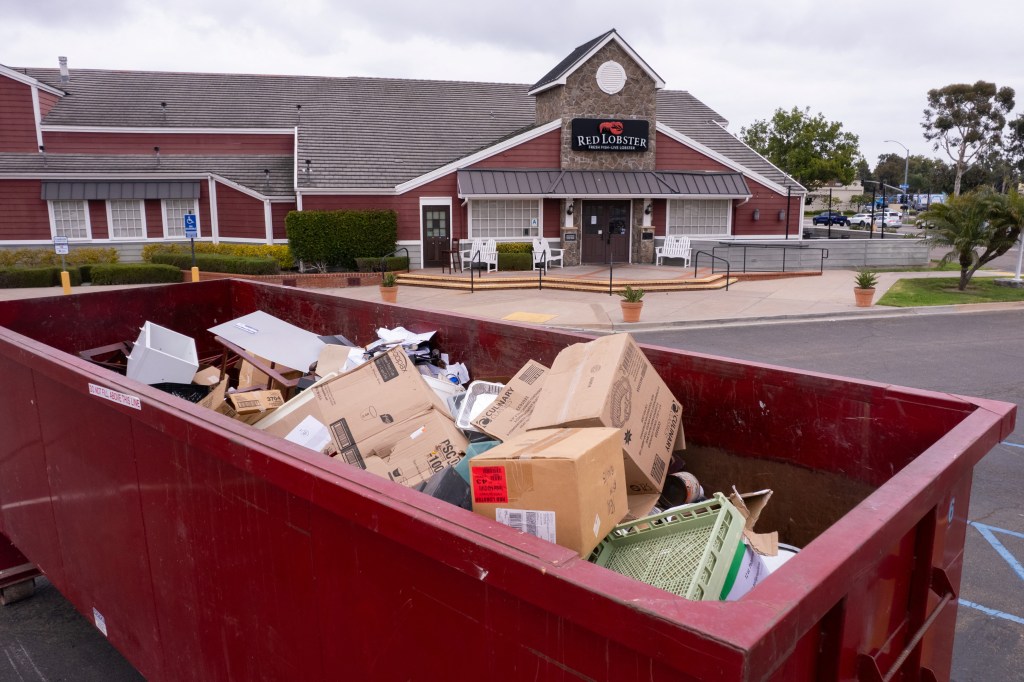 A dumpster full of cardboard boxes in front of a closed Red Lobster restaurant in San Diego, California, whose contents are up for auction.