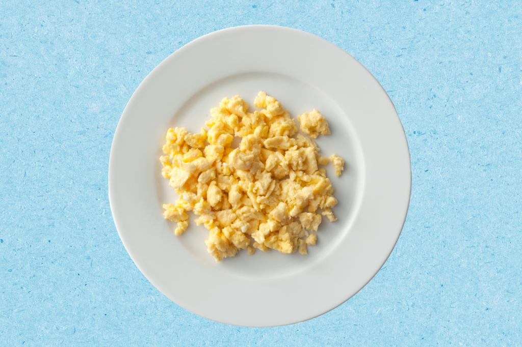 A plate of scrambled eggs on a blue paper texture background