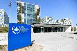 Exterior view of the International Criminal Court building in The Hague, Netherlands with a blue sign in front.