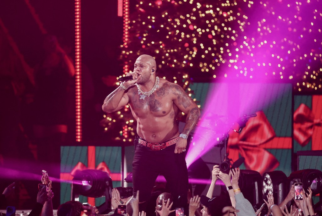 Flo Rida singing into a microphone on a stage during the iHeartRadio Jingle Ball in Inglewood, California