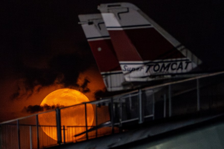 The flower moon sets behind Grumman F-14 Tomcat fighter jets at the Intrepid Museum, NYC.