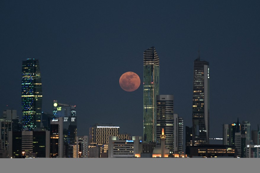 The full moon rises over Kuwait City.