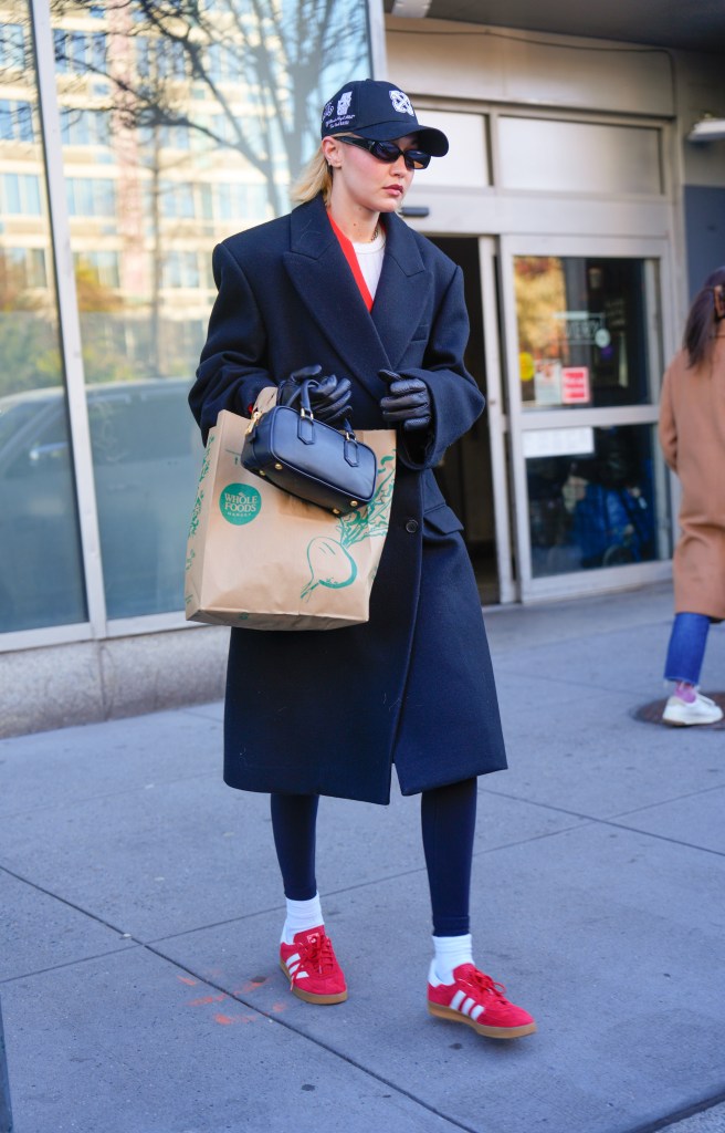 Gigi Hadid shopping at Whole Foods in New York City on March 24, 2024, wearing a coat and gloves and holding a bag