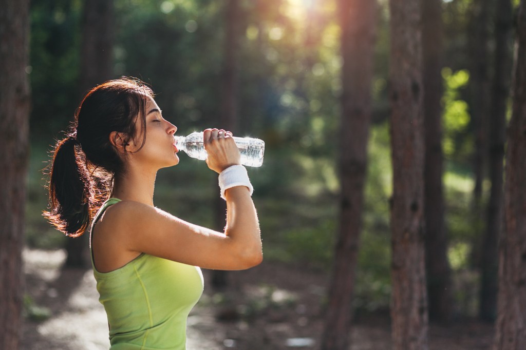 Girl drinking water from a bottle in a forest
